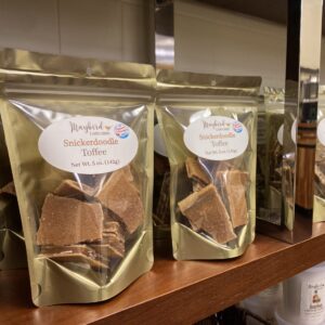 Snickerdoodle white gold toffee on shelf in gold bags