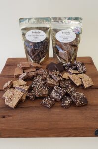 Loose toffee and two bags of toffee on a wooden board