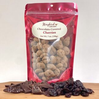 Chocolate covered cherries in 5 ounce bag with chocolate and dried cherries on cutting board